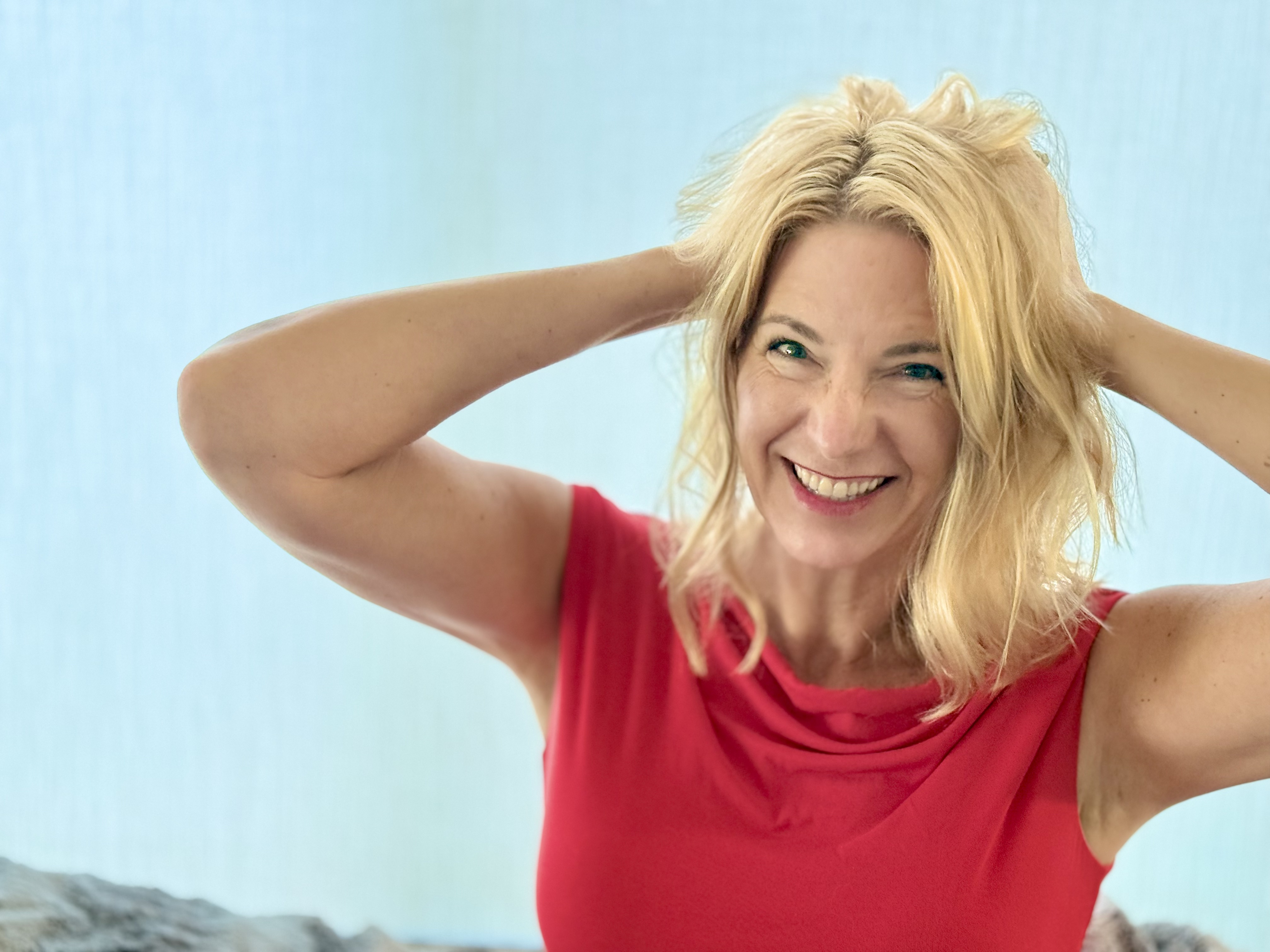 Theresa wearing a red shirt with her hands on her head - a goofy smiling pose.